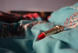 a red lipstick resting on a blue blanket